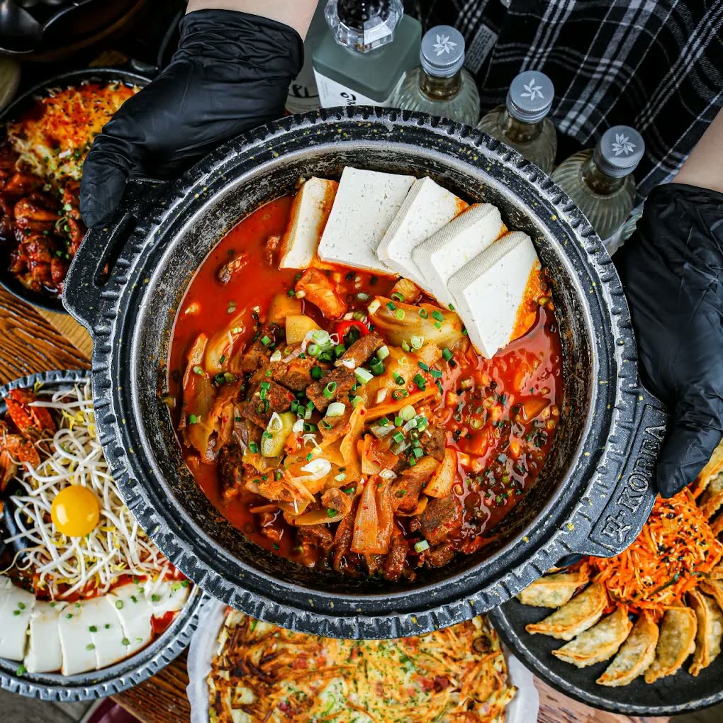 새벽짜글이 — 붉은 국물에 두툼한 돼지고기와 김치, 애호박이 자작하게 끓고 두부가 가장자리에 둘러져 있다