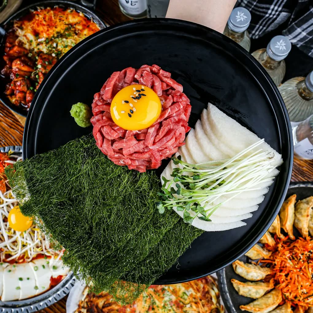 육회 한 접시 — 가늘게 썬 생소고기 가운데 노른자를 얹고, 김과 배, 새싹채소를 곁들였다
